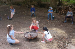 Children sat in the woods playing with a camp fire